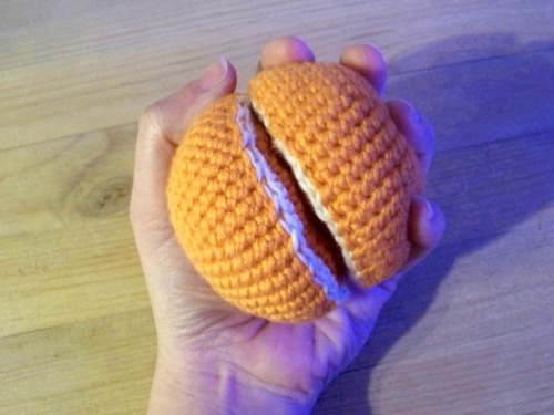 Une main tenant une orange en coton fabriquée en crochet