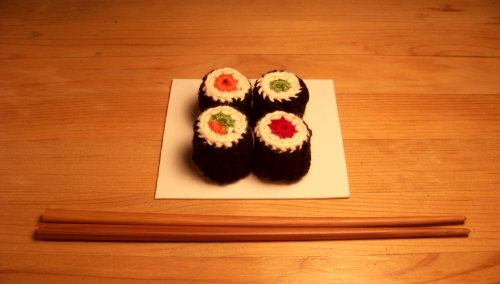 Des sushis en coton fabriqué en crochet présenté avec des baguettes