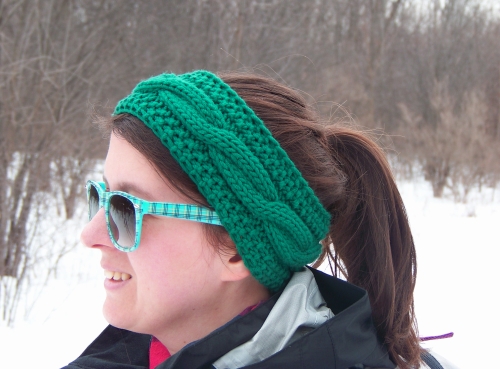 L'autrice dans un paysage de neige portant un bandeau tricoté avec une torsade.