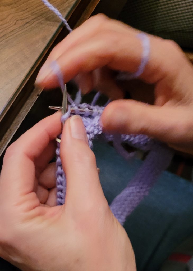 Le mouvement des mains sur des aiguilles à tricoter.